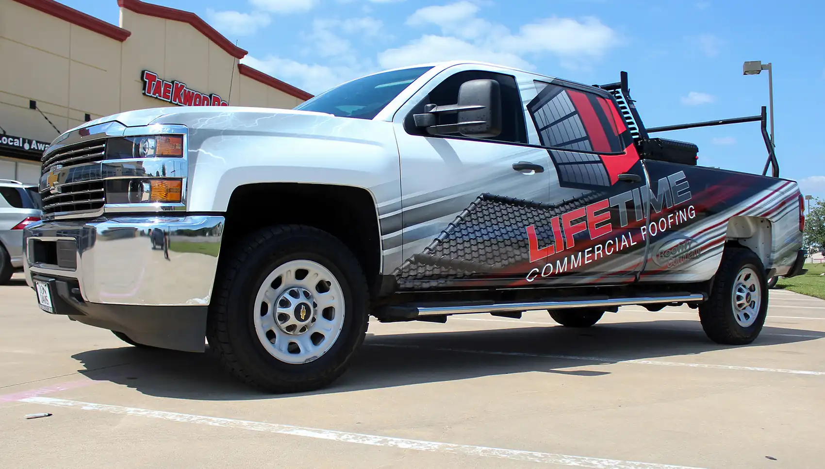 White pickup truck with a red and black wrap for Lifetime Commercial Roofing.
