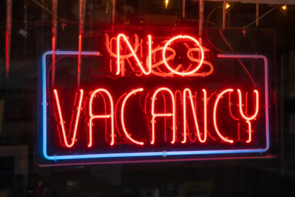 Closeup of the lighted signage saying "NO VACANCY" on the glass window