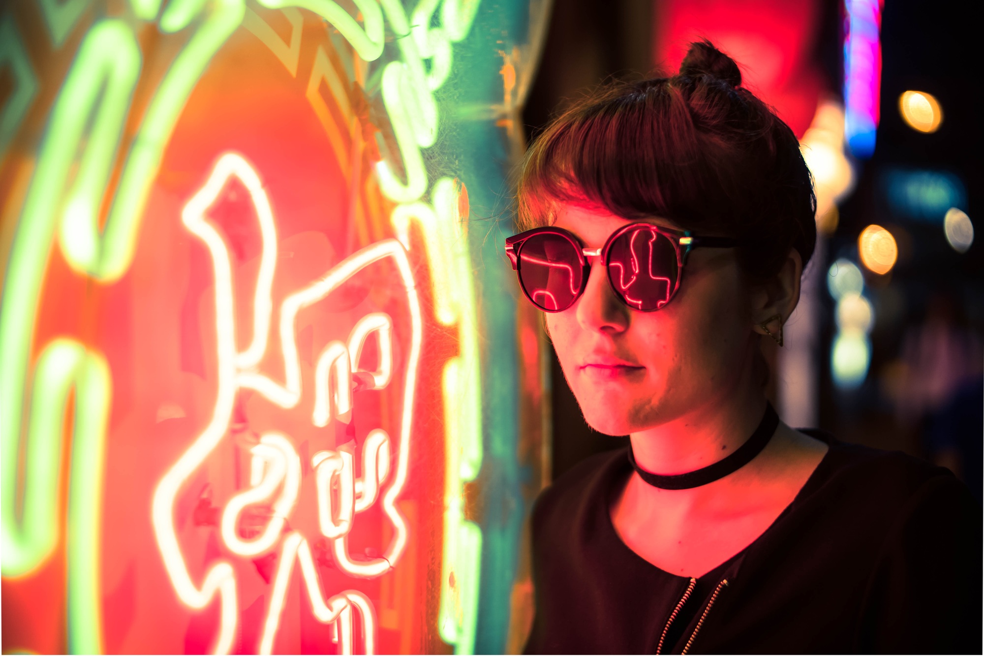 Woman wearing sunglasses standing beside neon signage